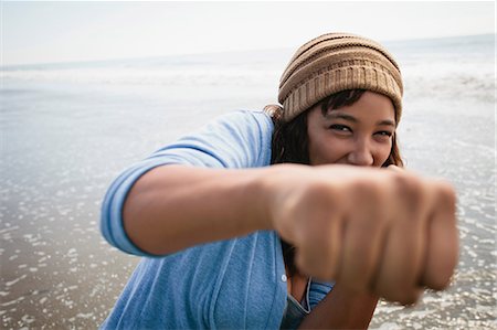 fight for a woman - Smiling woman making fists on beach Stock Photo - Premium Royalty-Free, Code: 614-06625475