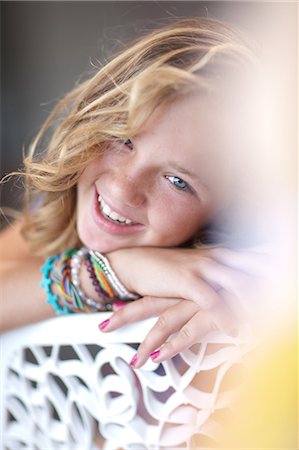 Smiling girl resting chin on bench Stock Photo - Premium Royalty-Free, Code: 614-06623434