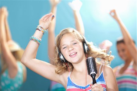 preteen girl arms raised - Girl singing into hairbrush Stock Photo - Premium Royalty-Free, Code: 614-06623491