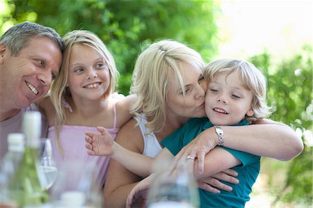four people hugs - Mother kissing son at table outdoors Stock Photo - Premium Royalty-Free, Code: 614-06623613