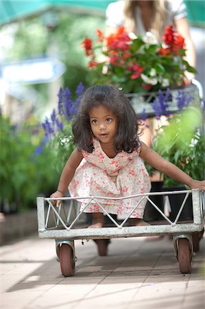 riding a shopping cart - Girl riding in cart in plant nursery Stock Photo - Premium Royalty-Free, Code: 614-06623715