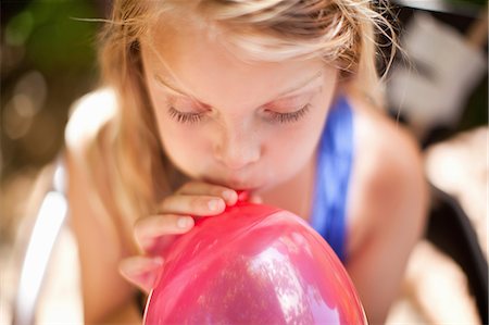 Girl blowing up balloon at party Stock Photo - Premium Royalty-Free, Code: 614-06623767