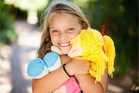 Smiling girl holding doll outdoors Stock Photo - Premium Royalty-Free, Code: 614-06623776