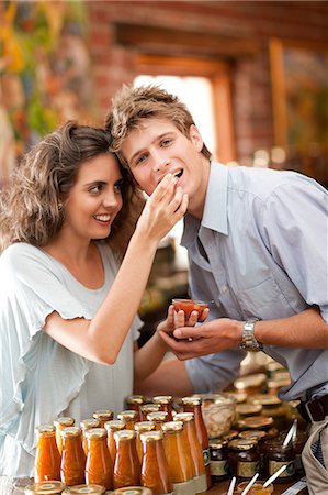 photo of a woman feeding her husband food - Couple tasting preserves in grocery Foto de stock - Sin royalties Premium, Código: 614-06623813