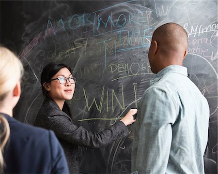 female motivating - Woman writing on blackboard, colleagues watching Stock Photo - Premium Royalty-Free, Code: 614-06718115