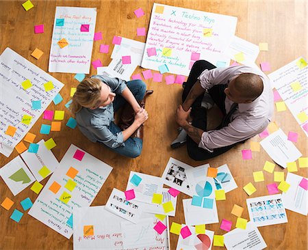 Colleagues sitting cross legged on floor with papers and adhesive notes Foto de stock - Sin royalties Premium, Código: 614-06718144