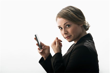 Businesswoman using smartphone as mirror Stock Photo - Premium Royalty-Free, Code: 614-06718234