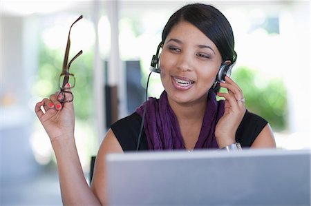 fone de ouvido - Businesswoman wearing headset at desk Foto de stock - Royalty Free Premium, Número: 614-06718464