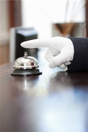 Bellhop ringing bell in hotel lobby Stock Photo - Premium Royalty-Free, Code: 614-06718495