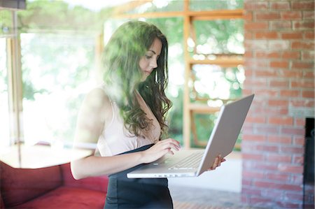 Woman using laptop in living room Stock Photo - Premium Royalty-Free, Code: 614-06718689