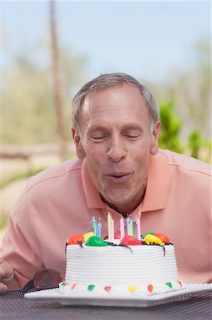 Older man blowing birthday candles Stock Photo - Premium Royalty-Free, Code: 614-06718972