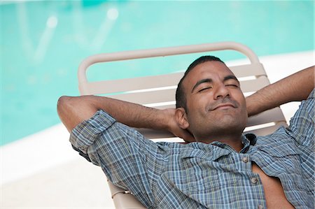 Man relaxing in lawn chair by pool Foto de stock - Sin royalties Premium, Código: 614-06719024