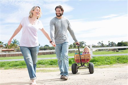 daughter riding on mother - Parents pulling son in wagon Stock Photo - Premium Royalty-Free, Code: 614-06719254