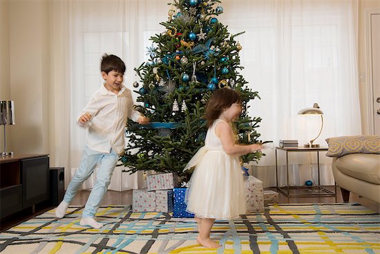 Children playing around Christmas tree Foto de stock - Sin royalties Premium, Código de la imagen: 614-06719323