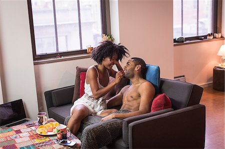 photo of a woman feeding her husband food - Couple relaxing together on sofa Stock Photo - Premium Royalty-Free, Code: 614-06719572