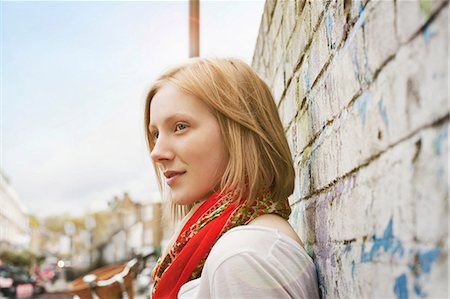 smiling - Woman leaning on brick wall Stock Photo - Premium Royalty-Free, Code: 614-06719628