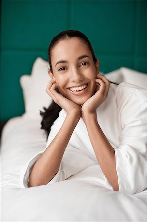 Woman in bathrobe smiling on bed Stock Photo - Premium Royalty-Free, Code: 614-06719648