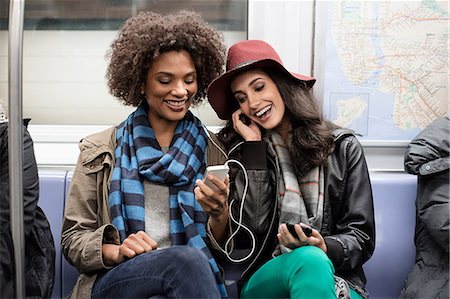 Women sharing earphones on subway Stock Photo - Premium Royalty-Free, Code: 614-06719733