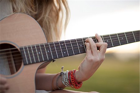 playing music - Woman playing guitar in grass Stock Photo - Premium Royalty-Free, Code: 614-06719789