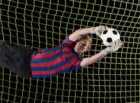 Soccer player catching ball in air Foto de stock - Sin royalties Premium, Código: 614-06719867