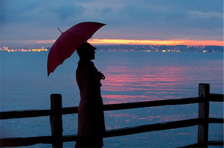 standing in rain - Woman with umbrella watching sunset Stock Photo - Premium Royalty-Free, Code: 614-06719884