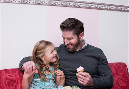 Father and daughter eating cupcakes Stock Photo - Premium Royalty-Free, Code: 614-06719945