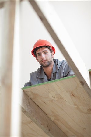 Laborer looking down from construction frame Stock Photo - Premium Royalty-Free, Code: 614-06814011