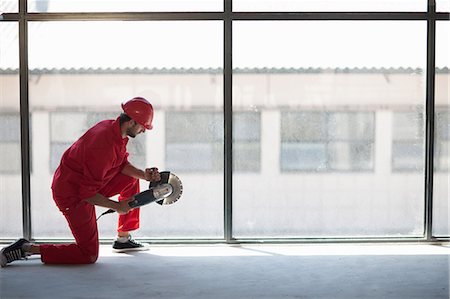 Laborer kneeling in front of window with circular saw Stock Photo - Premium Royalty-Free, Code: 614-06814026