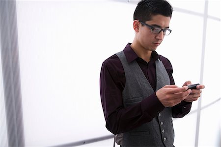 Young man texting on smartphone Stock Photo - Premium Royalty-Free, Code: 614-06814155