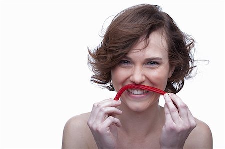 short hair brunette woman - Young woman holding candy underneath nose Stock Photo - Premium Royalty-Free, Code: 614-06814217