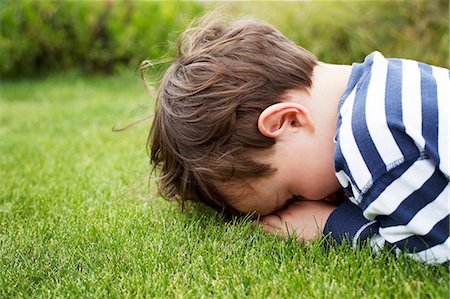 surprise boy - Male toddler hiding face down on grass Foto de stock - Sin royalties Premium, Código: 614-06814367