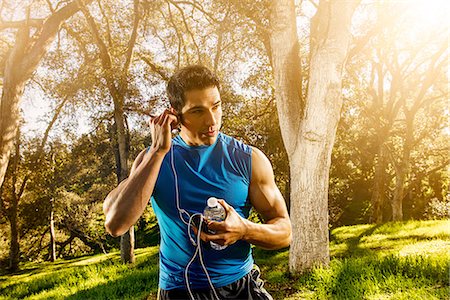 Young man exercising in forest wearing earphones Photographie de stock - Premium Libres de Droits, Code: 614-06813172