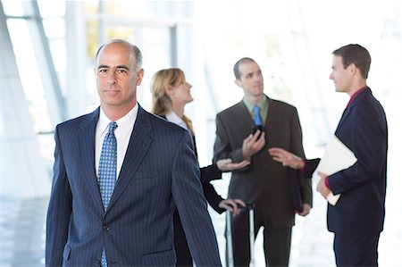 Mature businessman with colleagues in background Stock Photo - Premium Royalty-Free, Code: 614-06813204