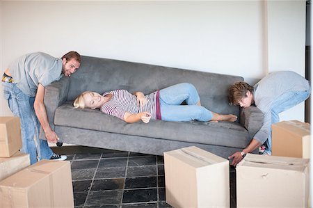 Young woman moving house on sofa being carried by men Stock Photo - Premium Royalty-Free, Code: 614-06813776