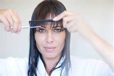 Mid adult woman cutting her own fringe Stock Photo - Premium Royalty-Free, Code: 614-06813812