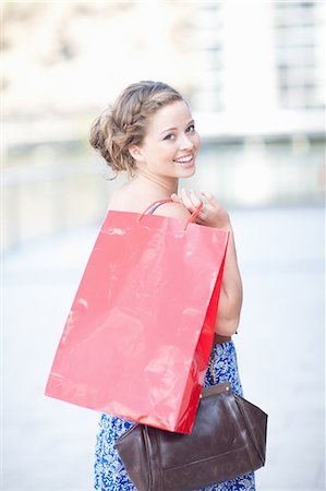 shopping bag - Young woman looking over shoulder at camera Stock Photo - Premium Royalty-Free, Code: 614-06813886