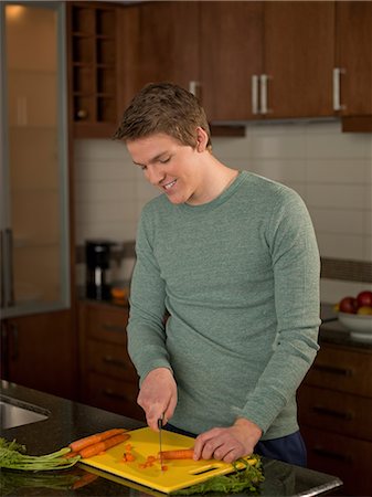 Young man slicing carrots in kitchen Stock Photo - Premium Royalty-Free, Code: 614-06895847