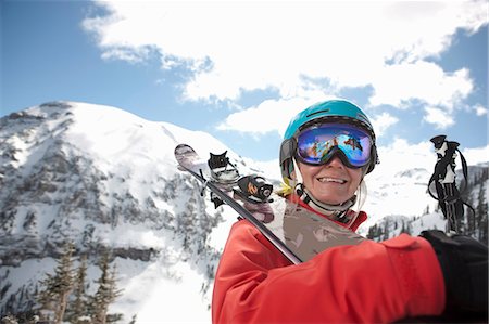 ski chalet - Young woman in skiwear holding skis over shoulder, smiling Stock Photo - Premium Royalty-Free, Code: 614-06896050