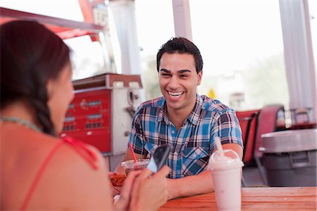 simsearch:614-06896148,k - Young man laughing in diner as girlfriend uses mobile phone Foto de stock - Sin royalties Premium, Código: 614-06896115