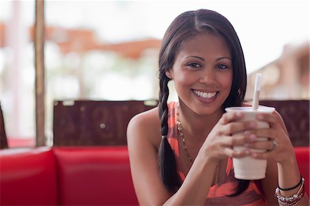 fast food photographs - Young woman holding milkshake in diner, smiling Stock Photo - Premium Royalty-Free, Code: 614-06896129