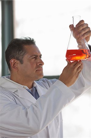 Mature scientist looking at liquid in volumetric flask Stock Photo - Premium Royalty-Free, Code: 614-06896121