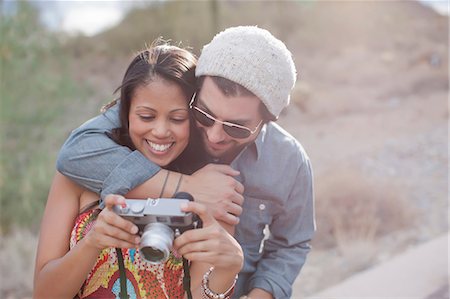 Couple embracing and holding camera on road trip, smiling Stock Photo - Premium Royalty-Free, Code: 614-06896197