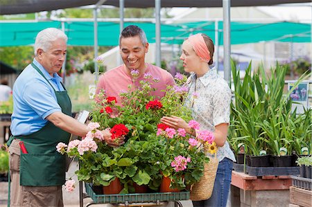 Senior gardener serving mature man and mid adult woman in garden centre Foto de stock - Sin royalties Premium, Código: 614-06896302