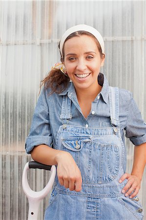 simsearch:614-06896287,k - Young woman in dungarees leaning on spade in garden centre, portrait Stock Photo - Premium Royalty-Free, Code: 614-06896323