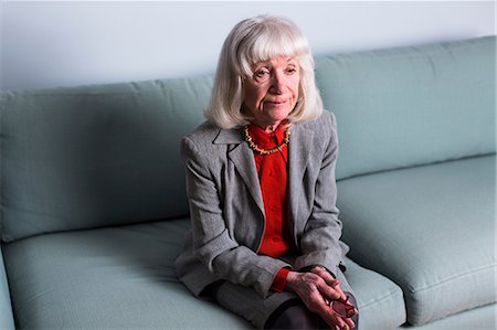 Senior woman sitting on sofa with blank expression Stock Photo - Premium Royalty-Free, Code: 614-06896549