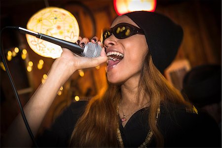 Woman wearing hat and sunglasses singing in microphone Photographie de stock - Premium Libres de Droits, Code: 614-06896593