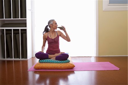 Woman sitting cross legged on cushion drinking water Photographie de stock - Premium Libres de Droits, Code: 614-06896669