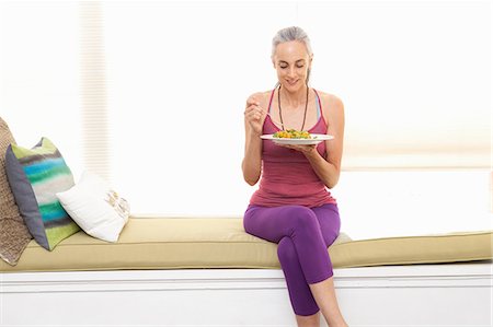 eating at home - Woman sitting on window seat eating lunch Stock Photo - Premium Royalty-Free, Code: 614-06896670