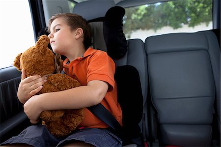 Boy looking out of car window holding teddy bear Stock Photo - Premium Royalty-Free, Code: 614-06896685