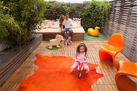 simsearch:614-03818600,k - Parents relaxing outdoor with children playing on patio Photographie de stock - Premium Libres de Droits, Code: 614-06896699